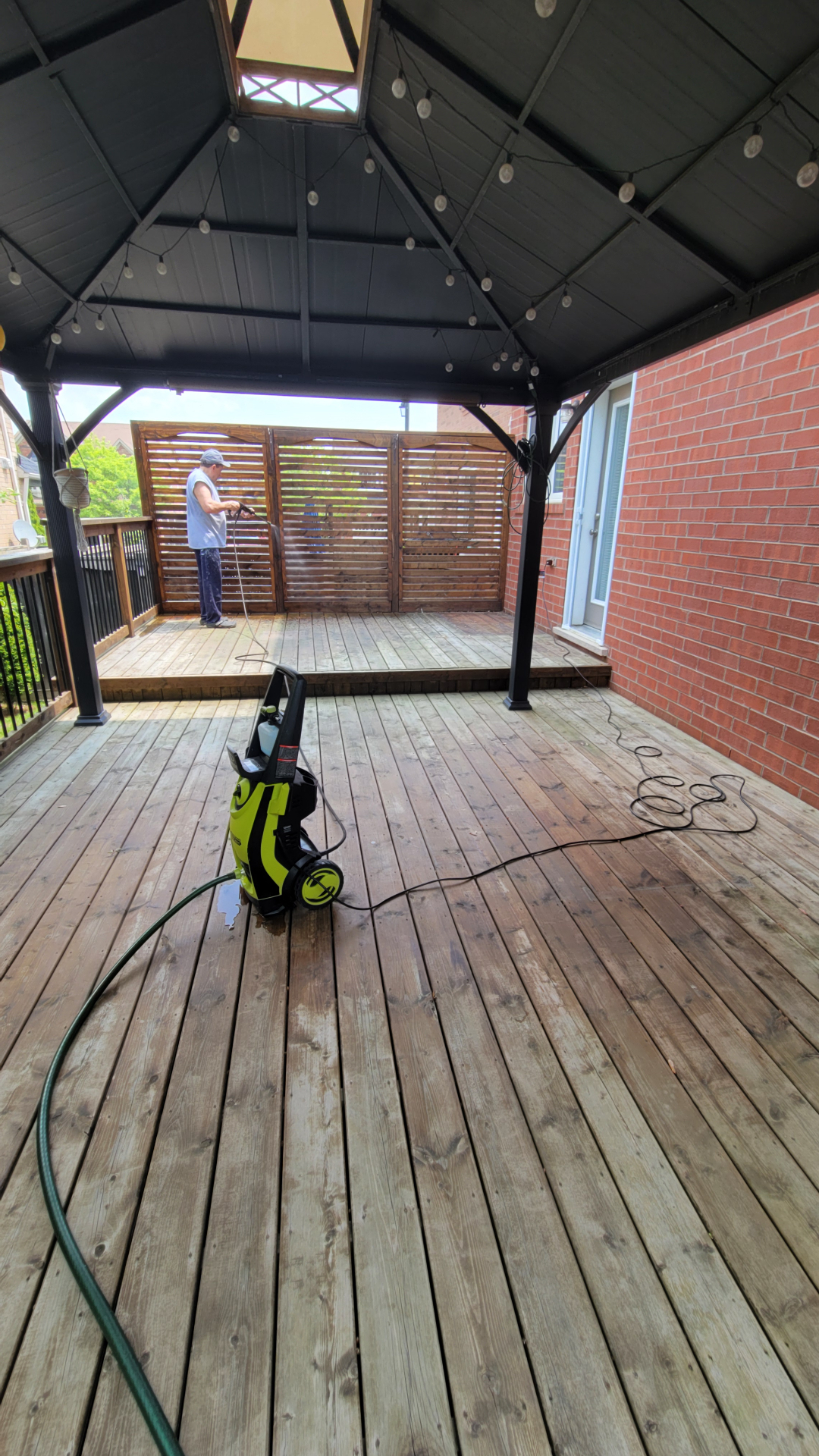 Pressure washer on a Newmarket back deck mid clean with a clear contrast between washed and unwashed boards