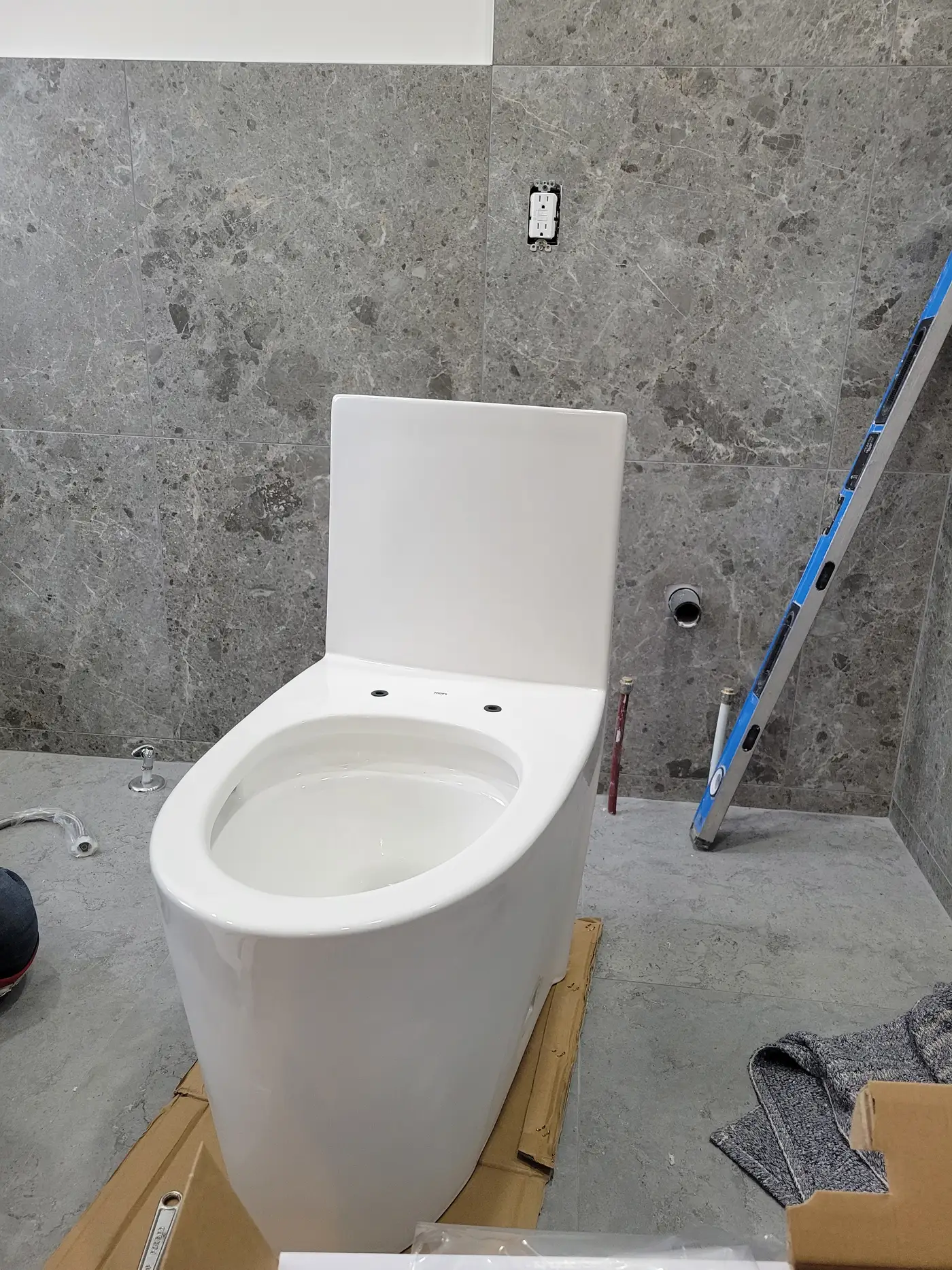 New white one-piece toilet installed on grey porcelain tile in the finished Richmond Hill bathroom