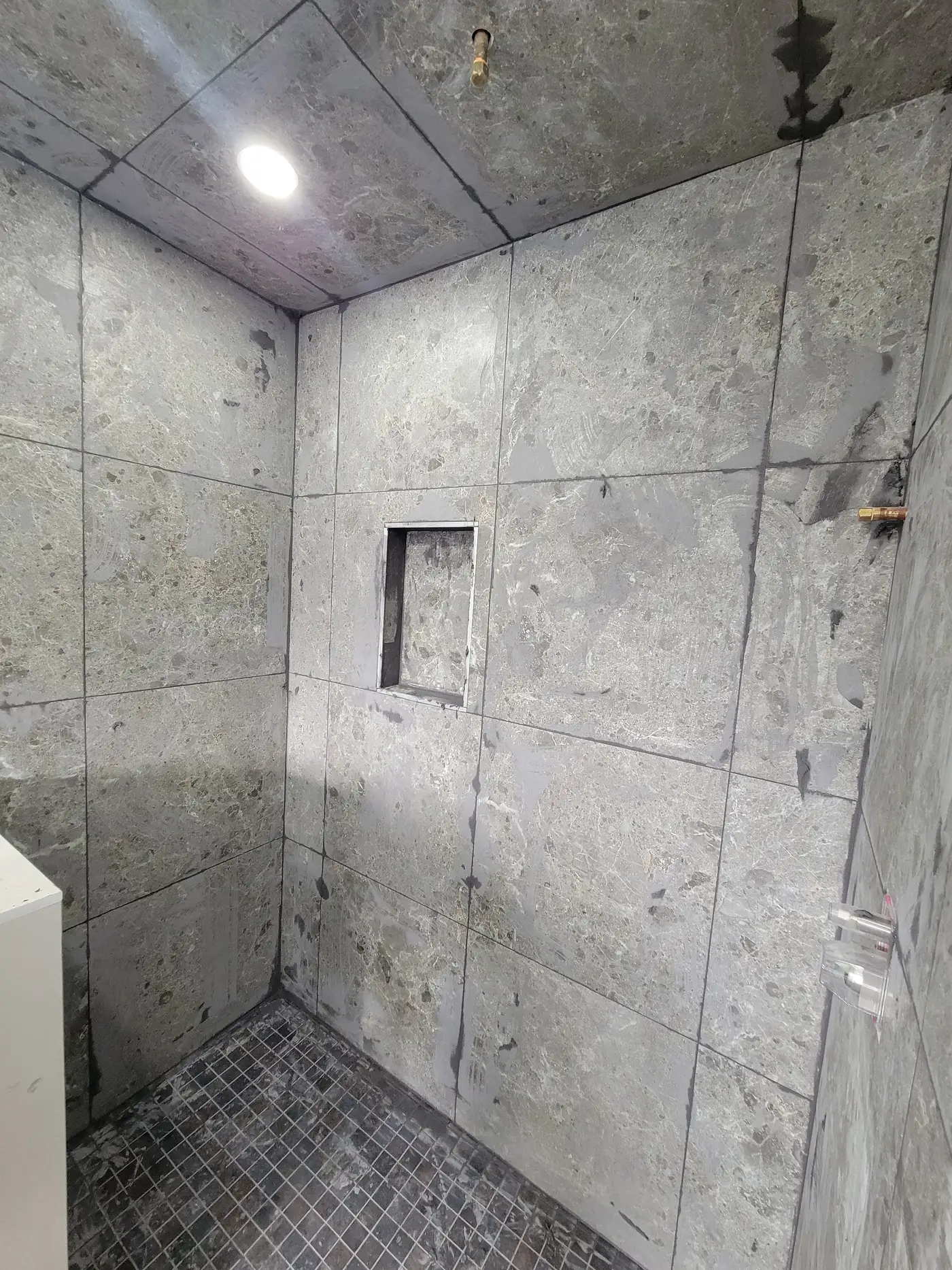 Finished grey porcelain shower wall in Richmond Hill with a recessed tiled niche and dark mosaic accent