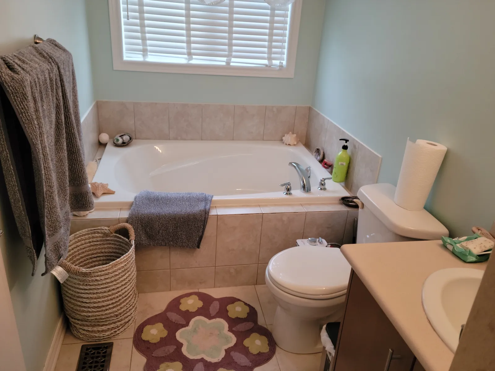 Dated builder bathroom in Aurora before renovation, with a beige-tiled drop-in soaker tub and toilet