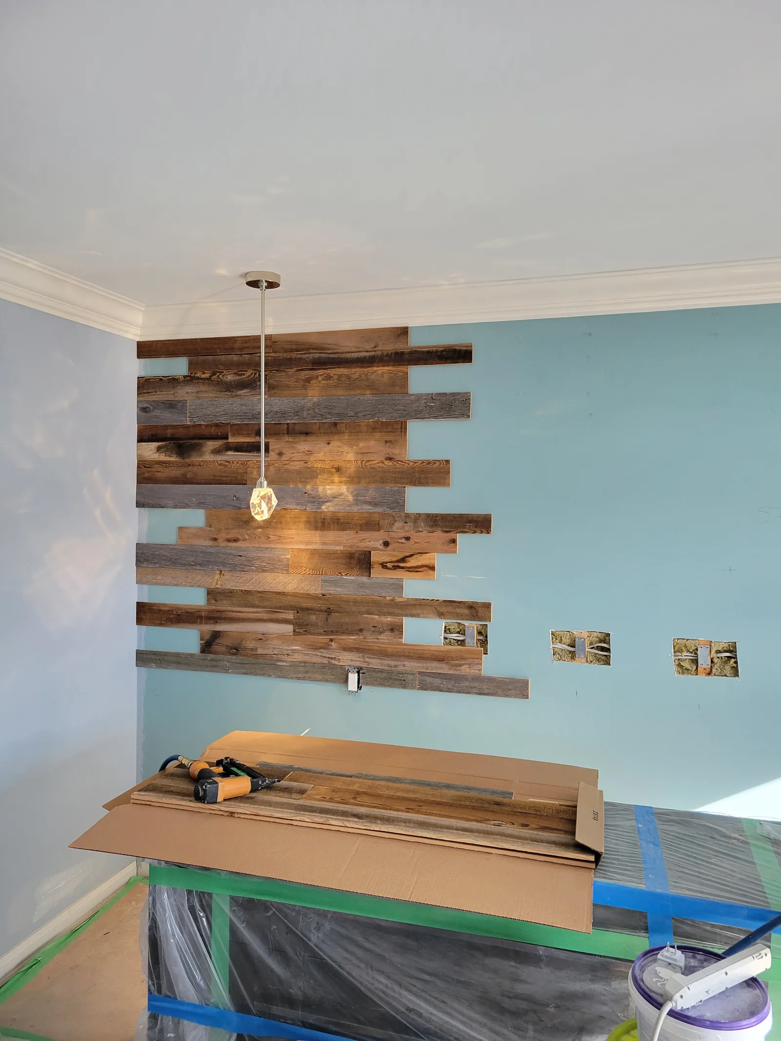 Reclaimed barn-board feature wall partway through installation in a Richmond Hill dining room, with planks staggered around a pendant light