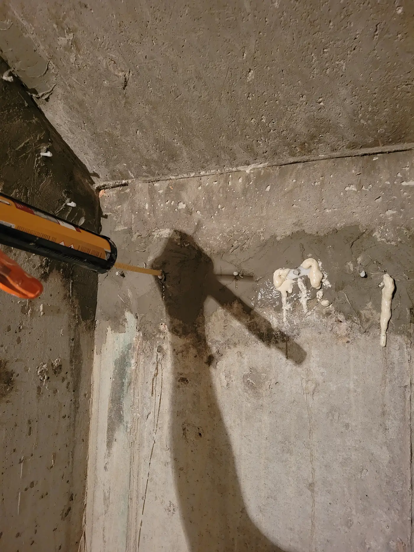 Polyurethane resin foaming back out of injection ports at a concrete corner joint, confirming the crack is filled