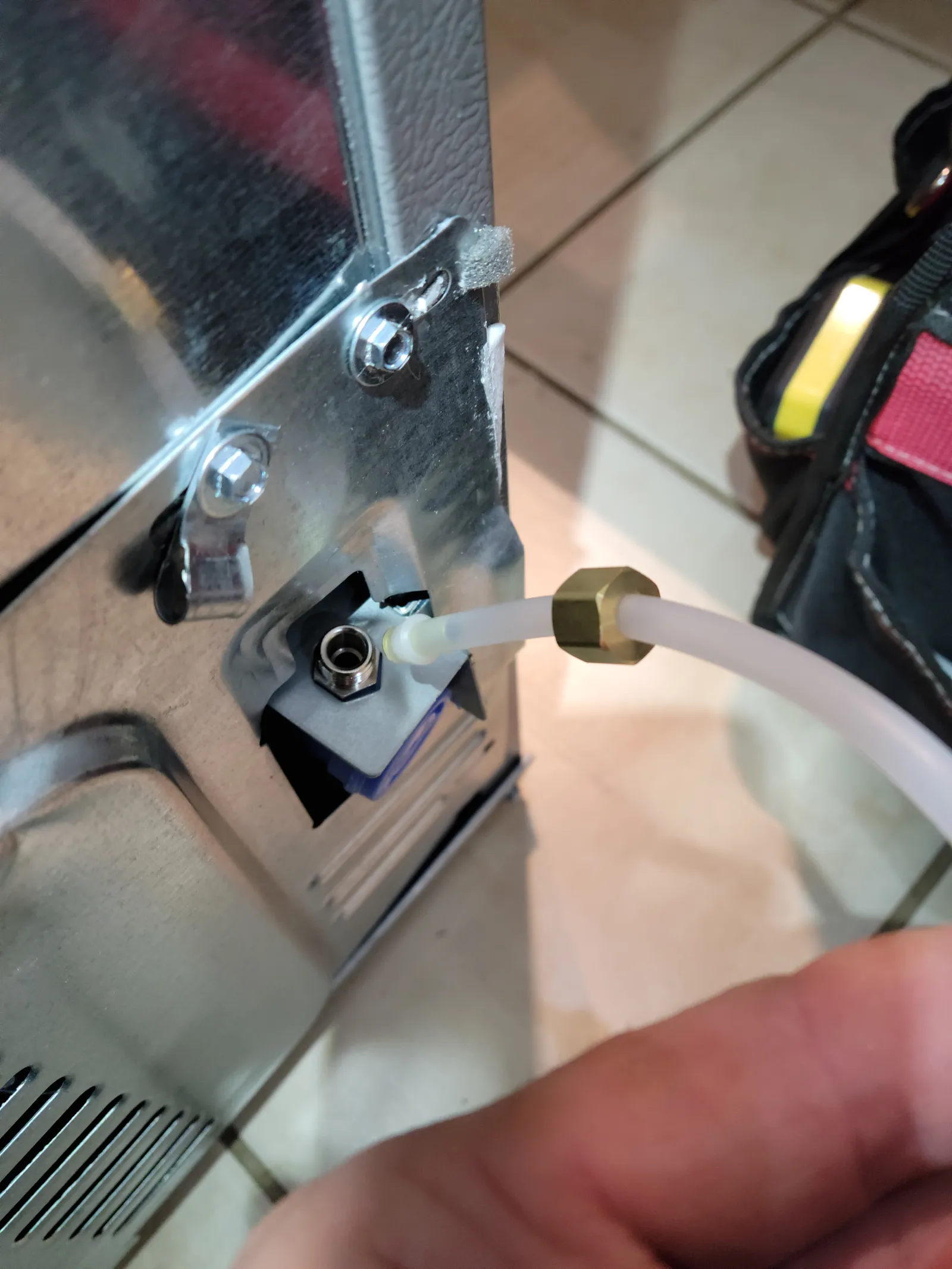 White water line connected with a compression nut to the water inlet on the back of a stainless fridge in Vaughan