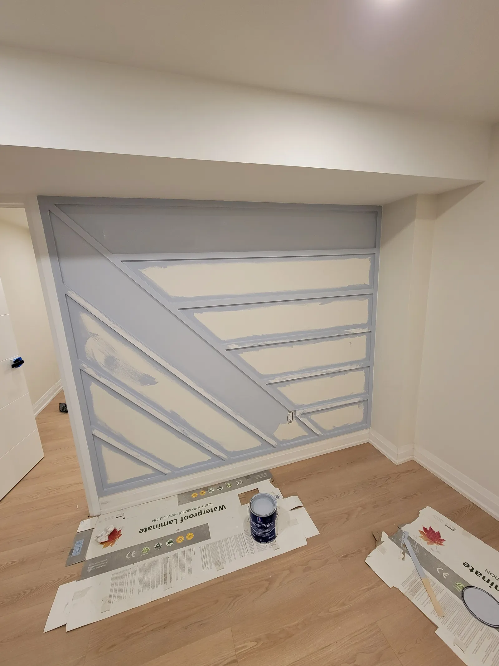Grey-blue paint being rolled over the new panelled feature wall in Aurora
