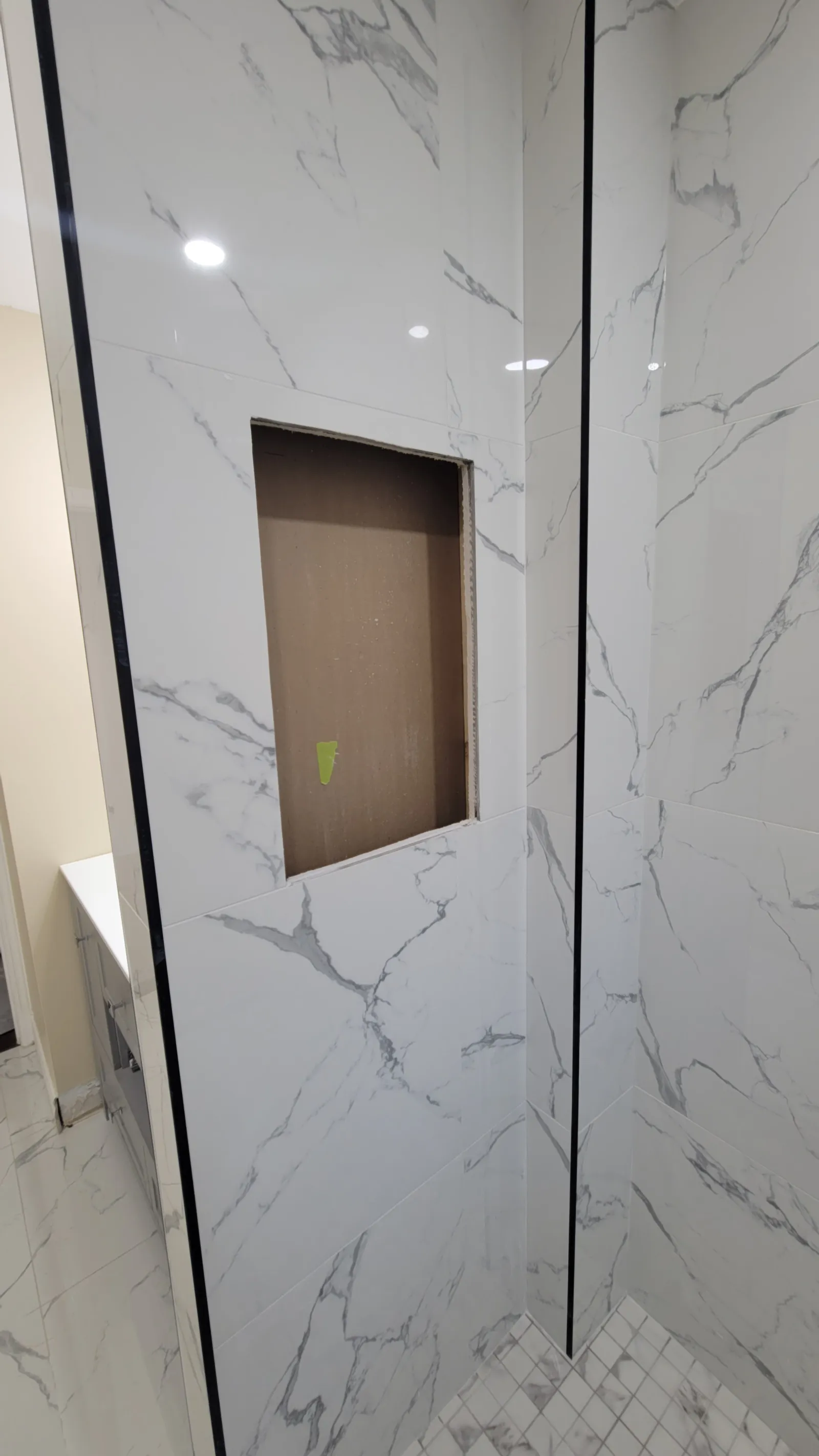 Re-tiled shower niche in Newmarket edged with slim black trim, awaiting its quartz shelf and back panel