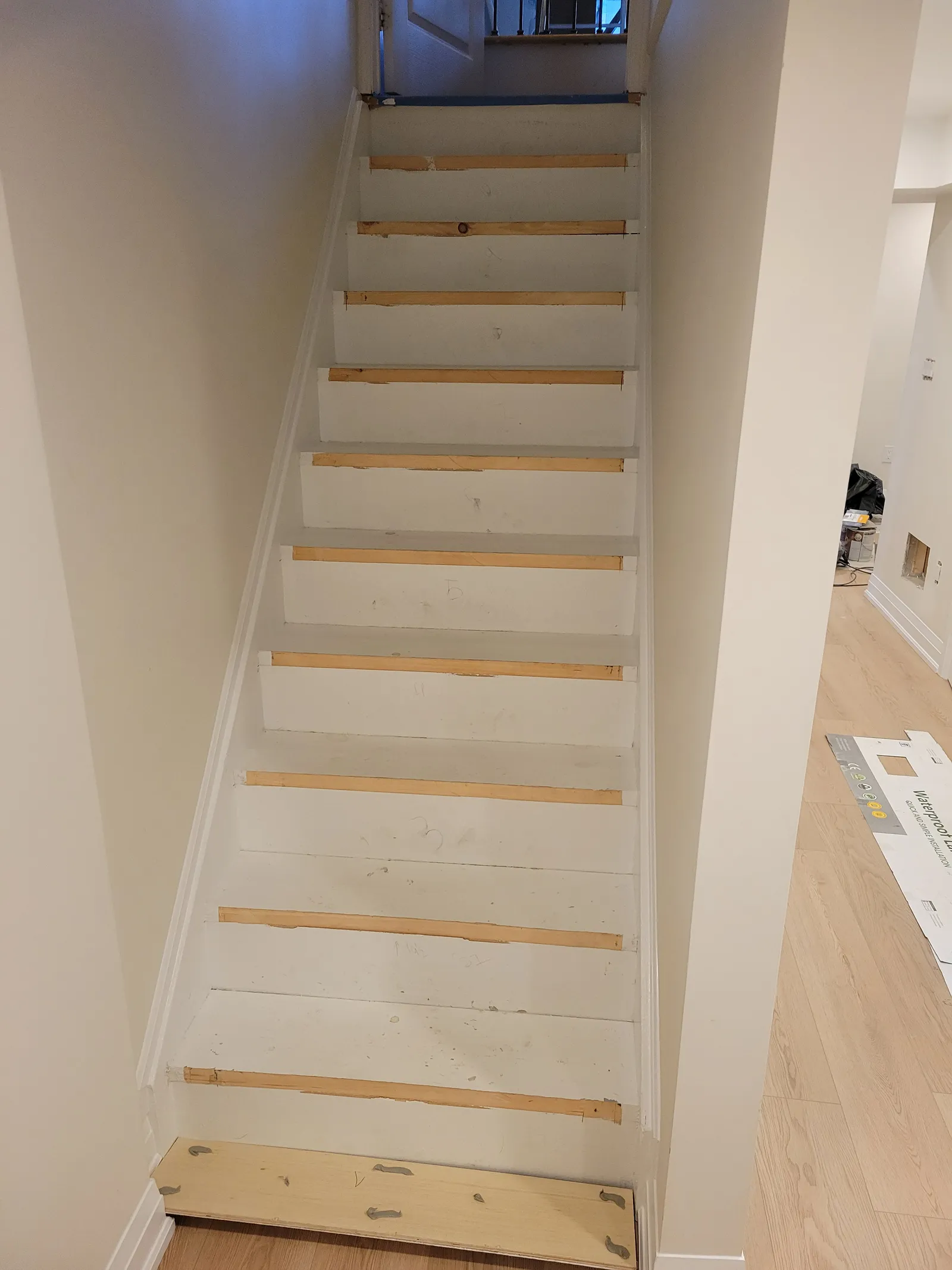 Staircase in Markham mid-refinish with white-painted risers and bare wood treads being prepared
