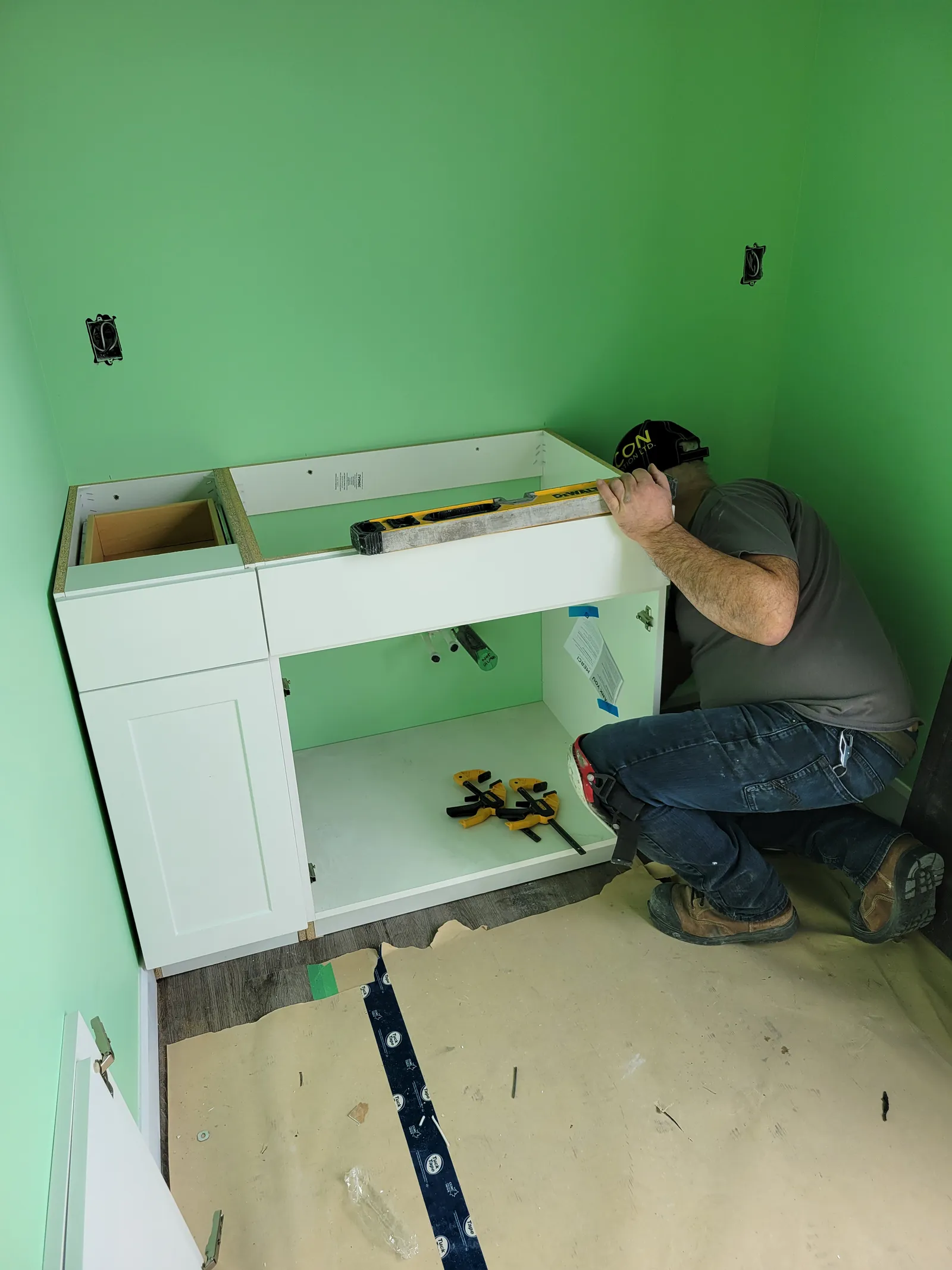 VOL Handyman installer levelling and clamping a new bathroom vanity cabinet against the wall in Stouffville